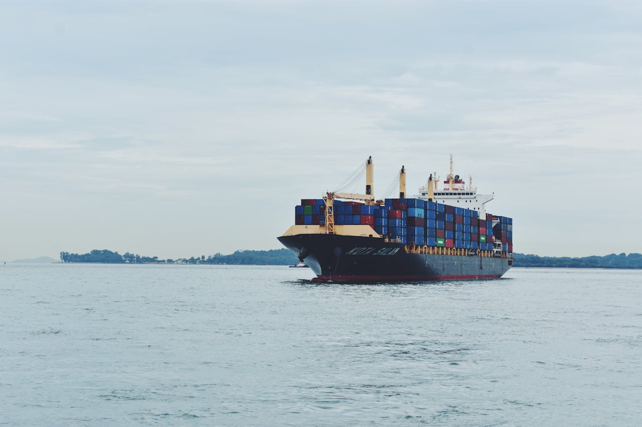 Large cargo ship transporting containers across a calm sea, symbolizing global logistics.